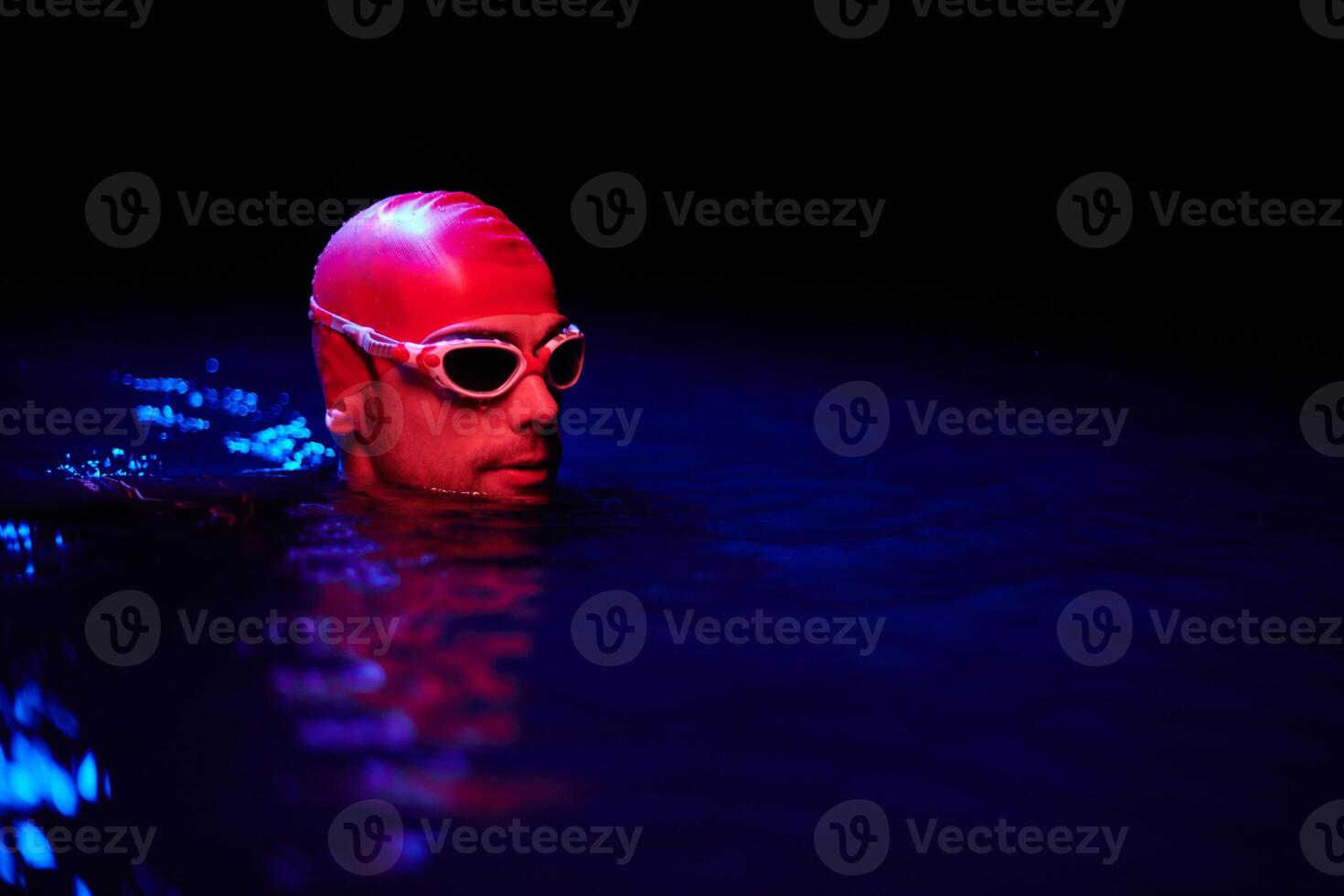 Authentic triathlete swimmer having a break during hard training on night neon gel light photo
