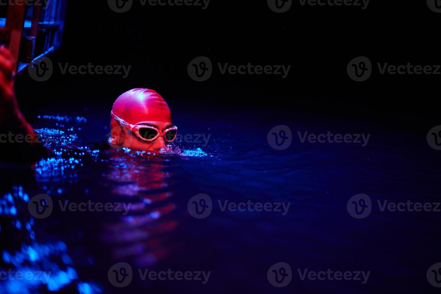 Authentic triathlete swimmer having a break during hard training on night neon gel light photo