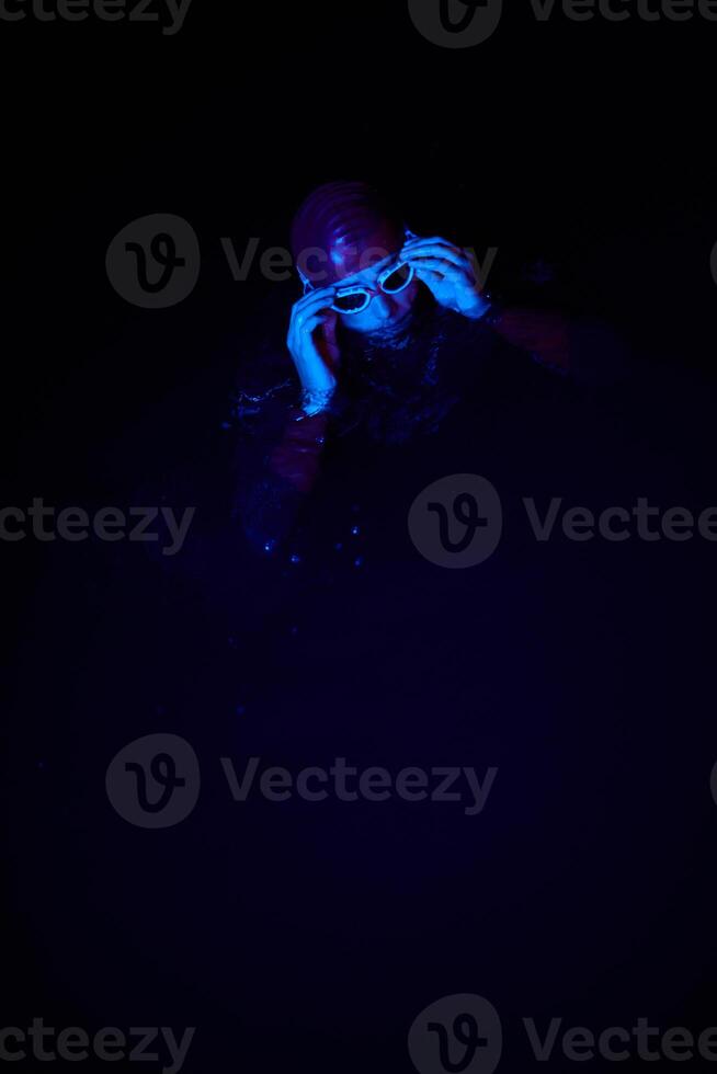 Authentic triathlete swimmer having a break during hard training on night neon gel light photo
