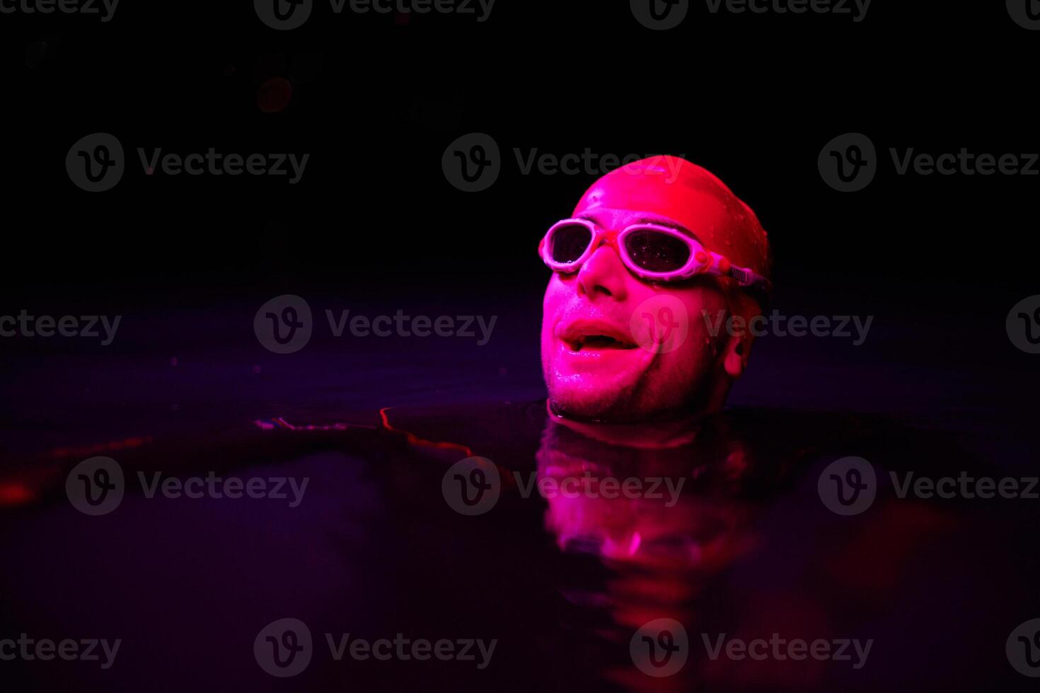 Authentic triathlete swimmer having a break during hard training on night neon gel light photo