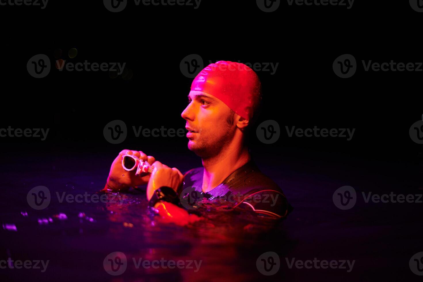 Authentic triathlete swimmer having a break during hard training on night neon gel light photo