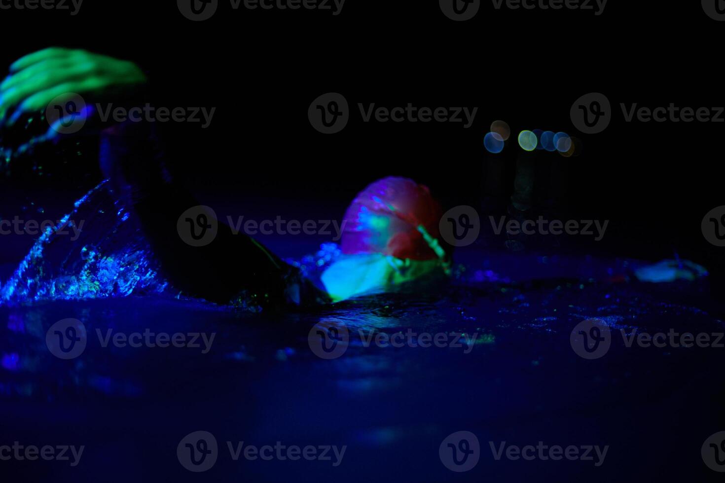 Authentic triathlete swimmer having a break during hard training on night neon gel light photo