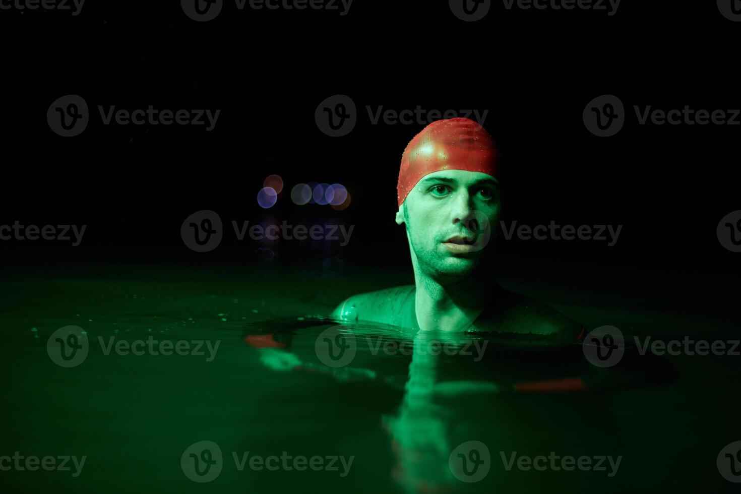 Authentic triathlete swimmer having a break during hard training on night neon gel light photo