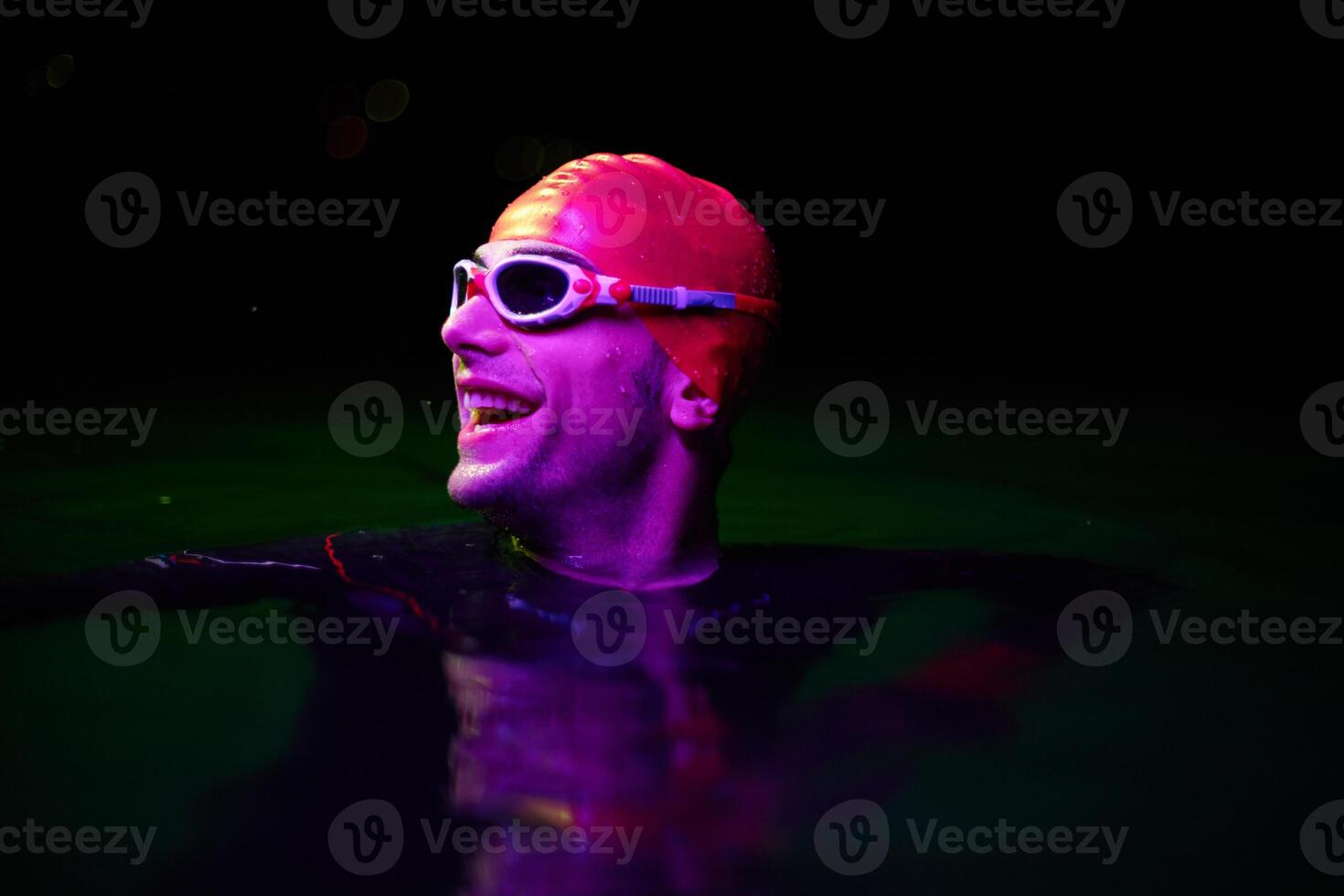Authentic triathlete swimmer having a break during hard training on night neon gel light photo