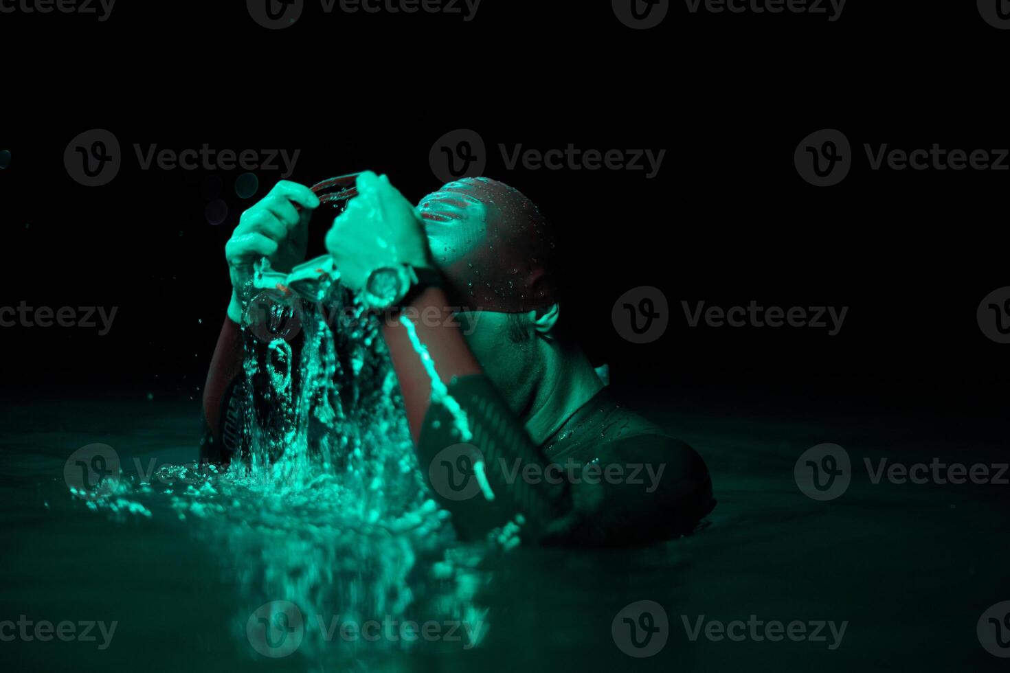 Authentic triathlete swimmer having a break during hard training on night neon gel light photo