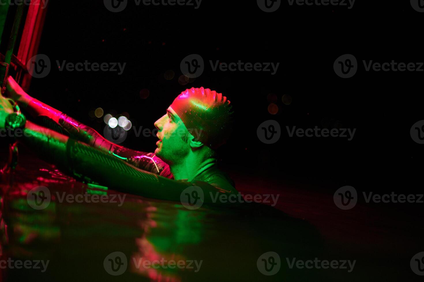 authentic triathlete swimmer having a break during hard training on night neon gel light photo