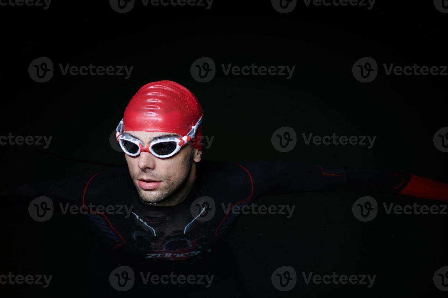 A determined professional triathlete undergoes rigorous night time training in cold waters, showcasing dedication and resilience in preparation for an upcoming triathlon swim competition photo