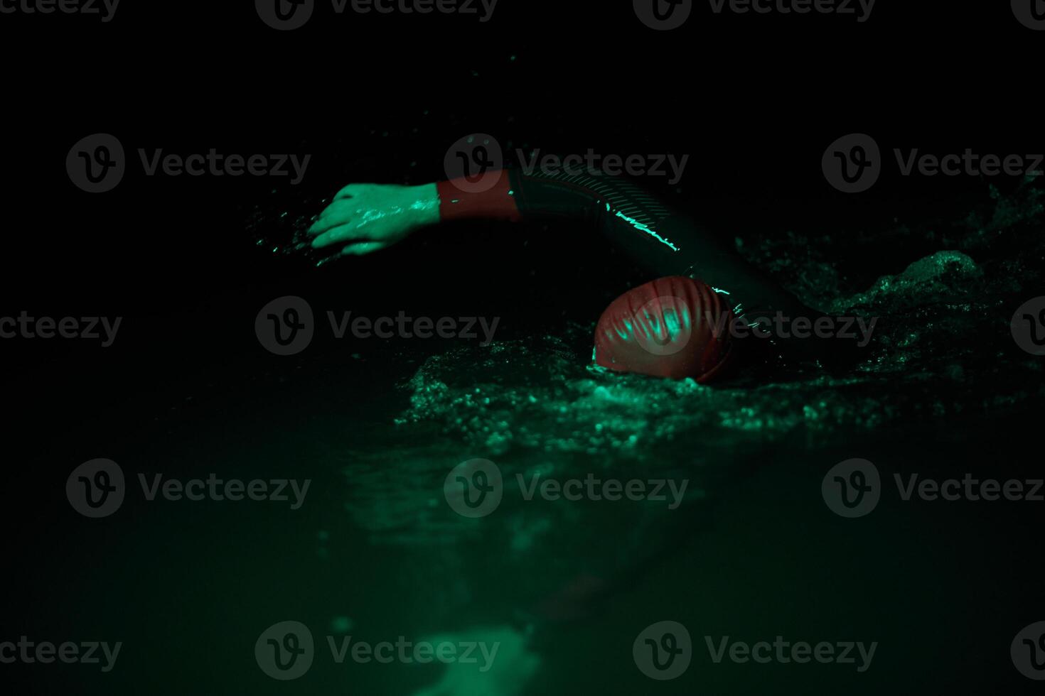 Authentic triathlete swimmer having a break during hard training on night neon gel light photo