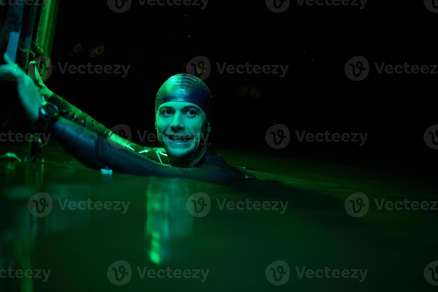 authentic triathlete swimmer having a break during hard training on night neon gel light photo