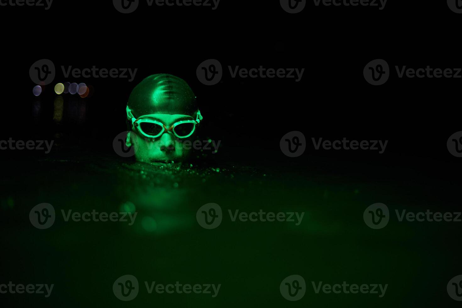 Authentic triathlete swimmer having a break during hard training on night neon gel light photo