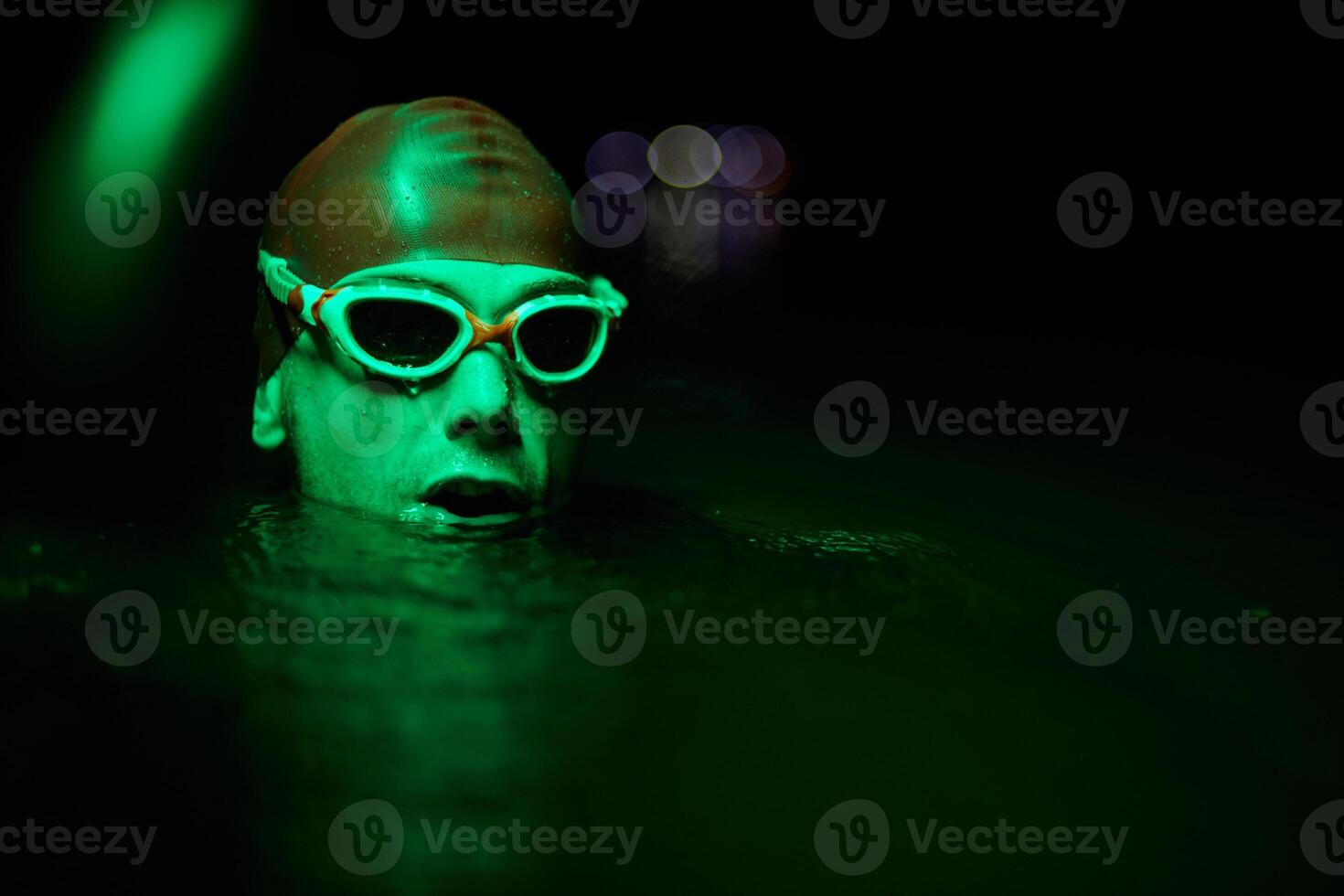Authentic triathlete swimmer having a break during hard training on night neon gel light photo