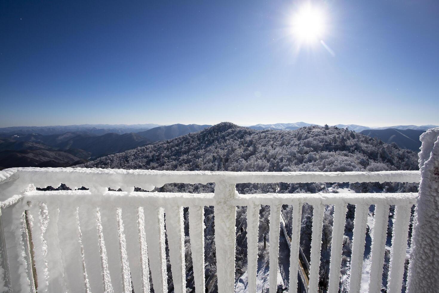 The balcony railing is covered with frost with snow-white background. View from the balcony during a snowfall. Selective focus. photo