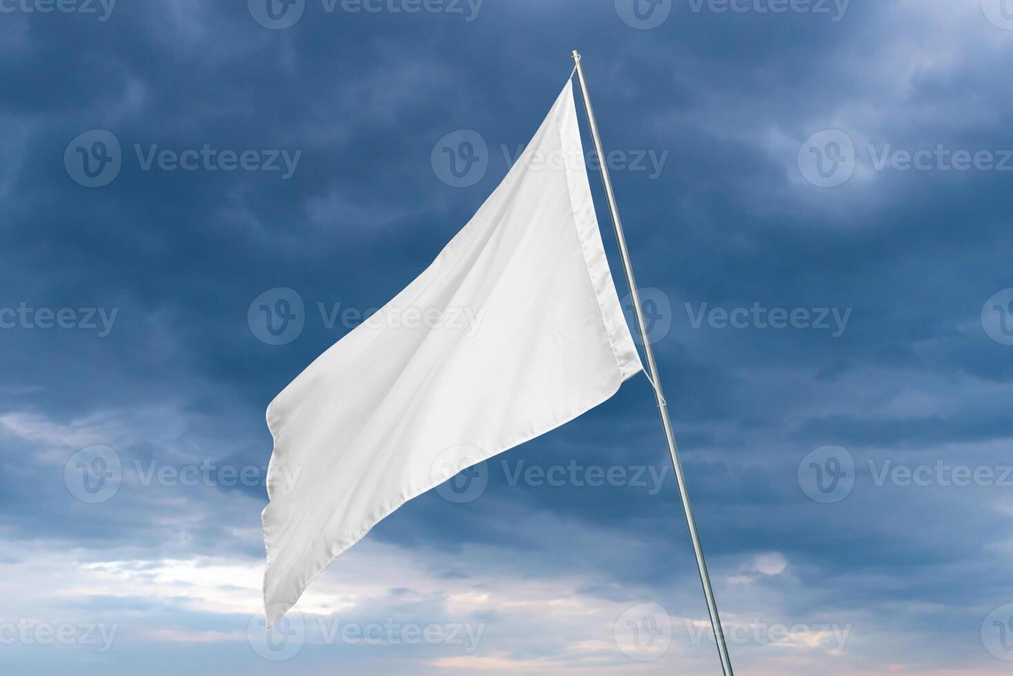 A white flag waves in the wind with dark clouds in the background, perfect for state or advertising flag mockup with clean texture photo