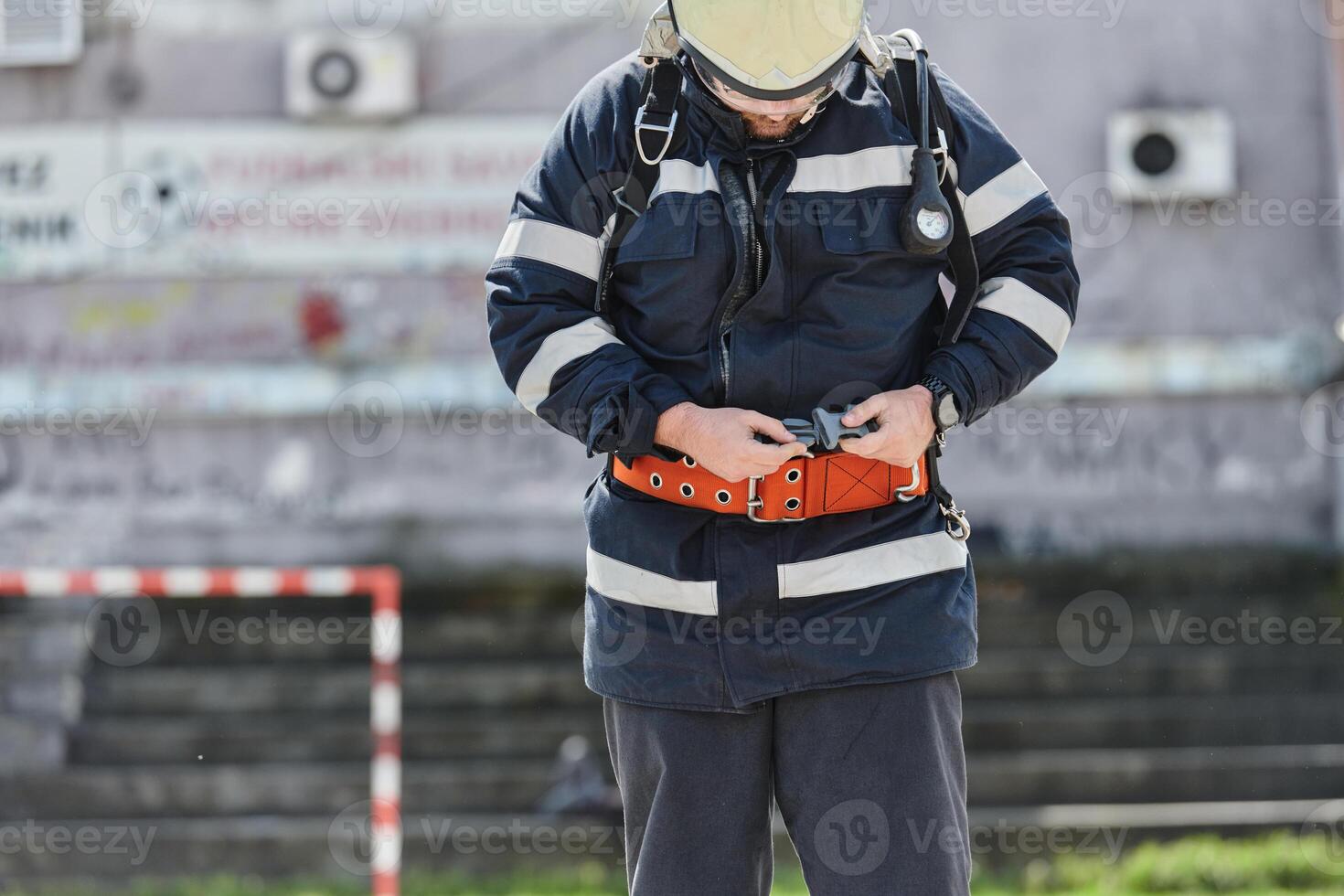 A firefighter dons the essential components of their professional gear, embodying resilience, commitment, and readiness as they gear up for a hazardous firefighting mission, a testament to their photo