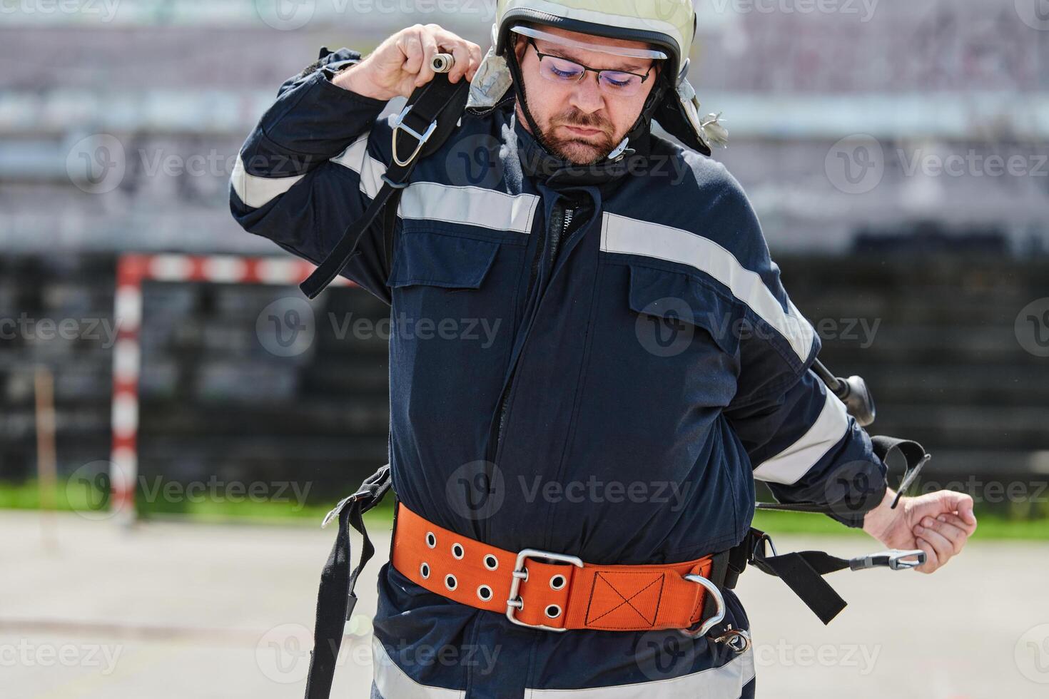 A firefighter dons the essential components of their professional gear, embodying resilience, commitment, and readiness as they gear up for a hazardous firefighting mission, a testament to their photo