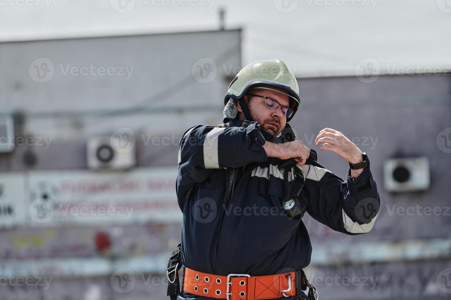 A firefighter dons the essential components of their professional gear, embodying resilience, commitment, and readiness as they gear up for a hazardous firefighting mission, a testament to their photo