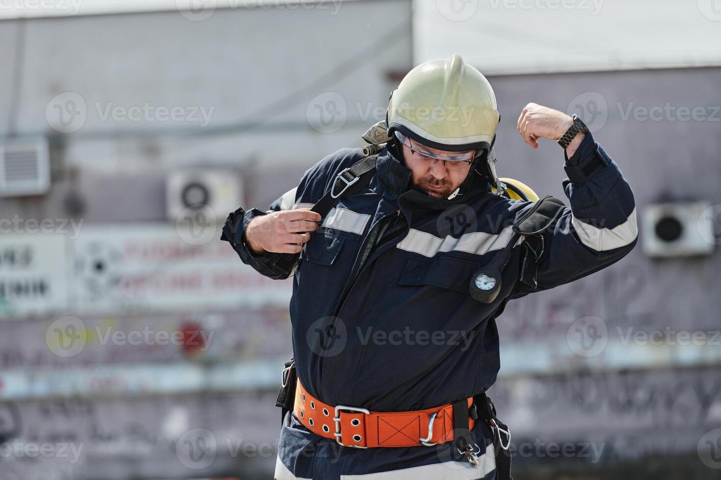 A firefighter dons the essential components of their professional gear, embodying resilience, commitment, and readiness as they gear up for a hazardous firefighting mission, a testament to their photo