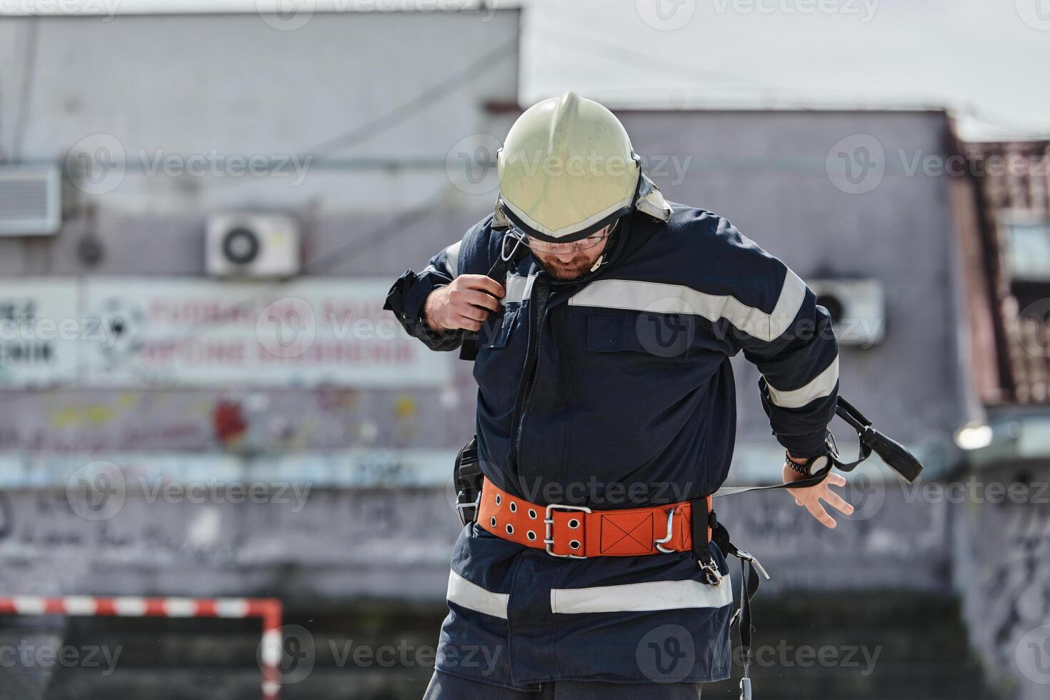 A firefighter dons the essential components of their professional gear, embodying resilience, commitment, and readiness as they gear up for a hazardous firefighting mission, a testament to their photo