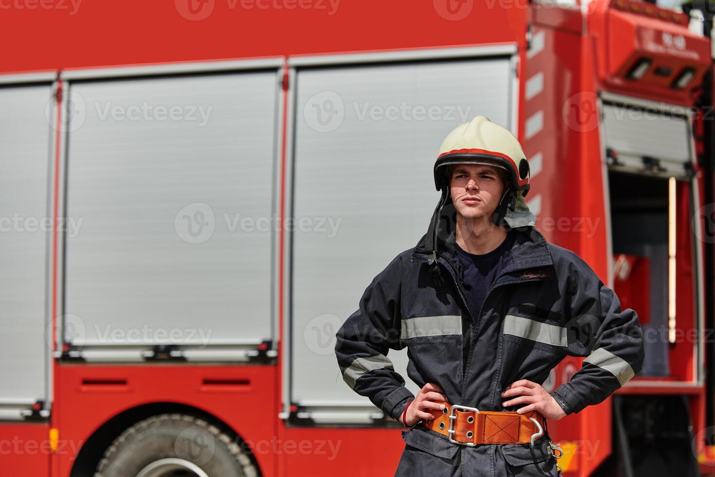 Firefighter Stands Proudly with Professional Gear Beside Fire Truck After Intense Training photo
