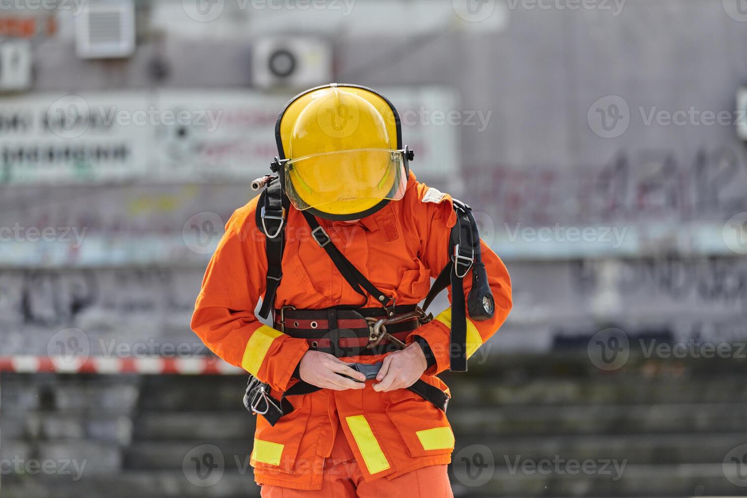 A firefighter dons the essential components of their professional gear, embodying resilience, commitment, and readiness as they gear up for a hazardous firefighting mission, a testament to their photo
