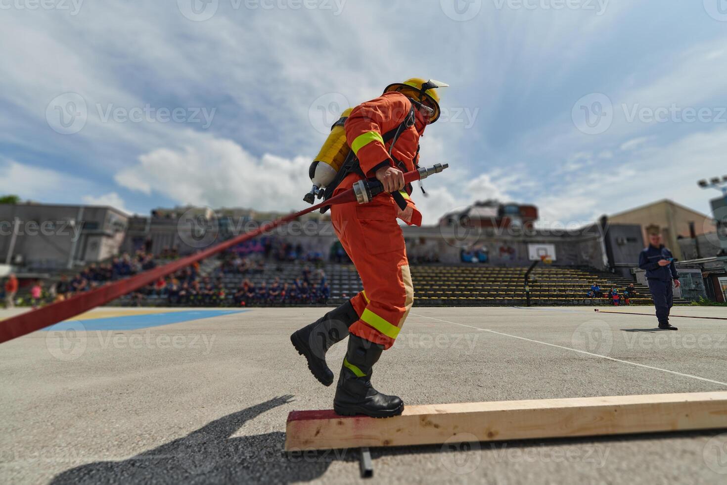 In a dynamic display of synchronized teamwork, firefighters hustle to carry, connect, and deploy firefighting hoses with precision, showcasing their intensive training and readiness for challenging photo