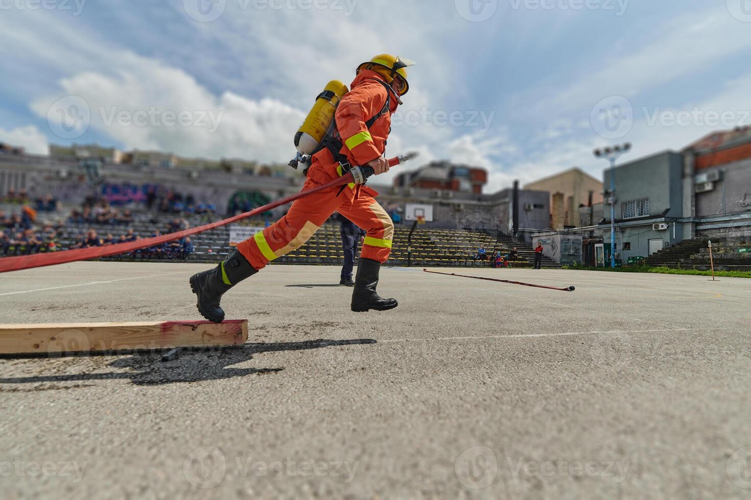 In a dynamic display of synchronized teamwork, firefighters hustle to carry, connect, and deploy firefighting hoses with precision, showcasing their intensive training and readiness for challenging photo
