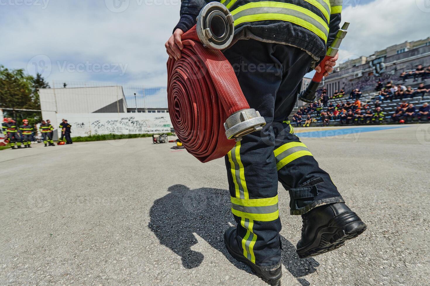 In a dynamic display of synchronized teamwork, firefighters hustle to carry, connect, and deploy firefighting hoses with precision, showcasing their intensive training and readiness for challenging photo