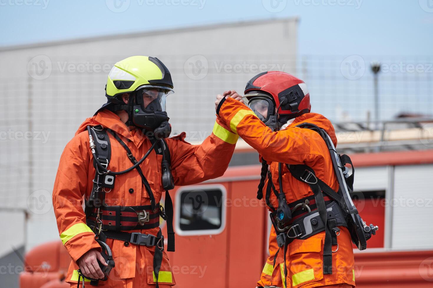 A unified team of firefighters, adorned in their uniforms, engages in a heartfelt celebration marked by triumphant salutes and cheers, embodying the joy and gratitude following the successful photo