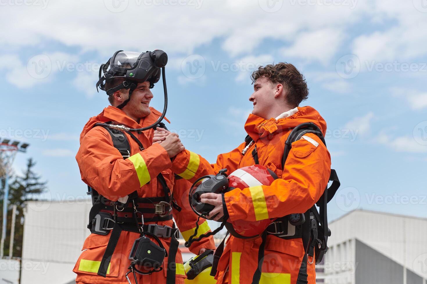 A unified team of firefighters, adorned in their uniforms, engages in a heartfelt celebration marked by triumphant salutes and cheers, embodying the joy and gratitude following the successful photo