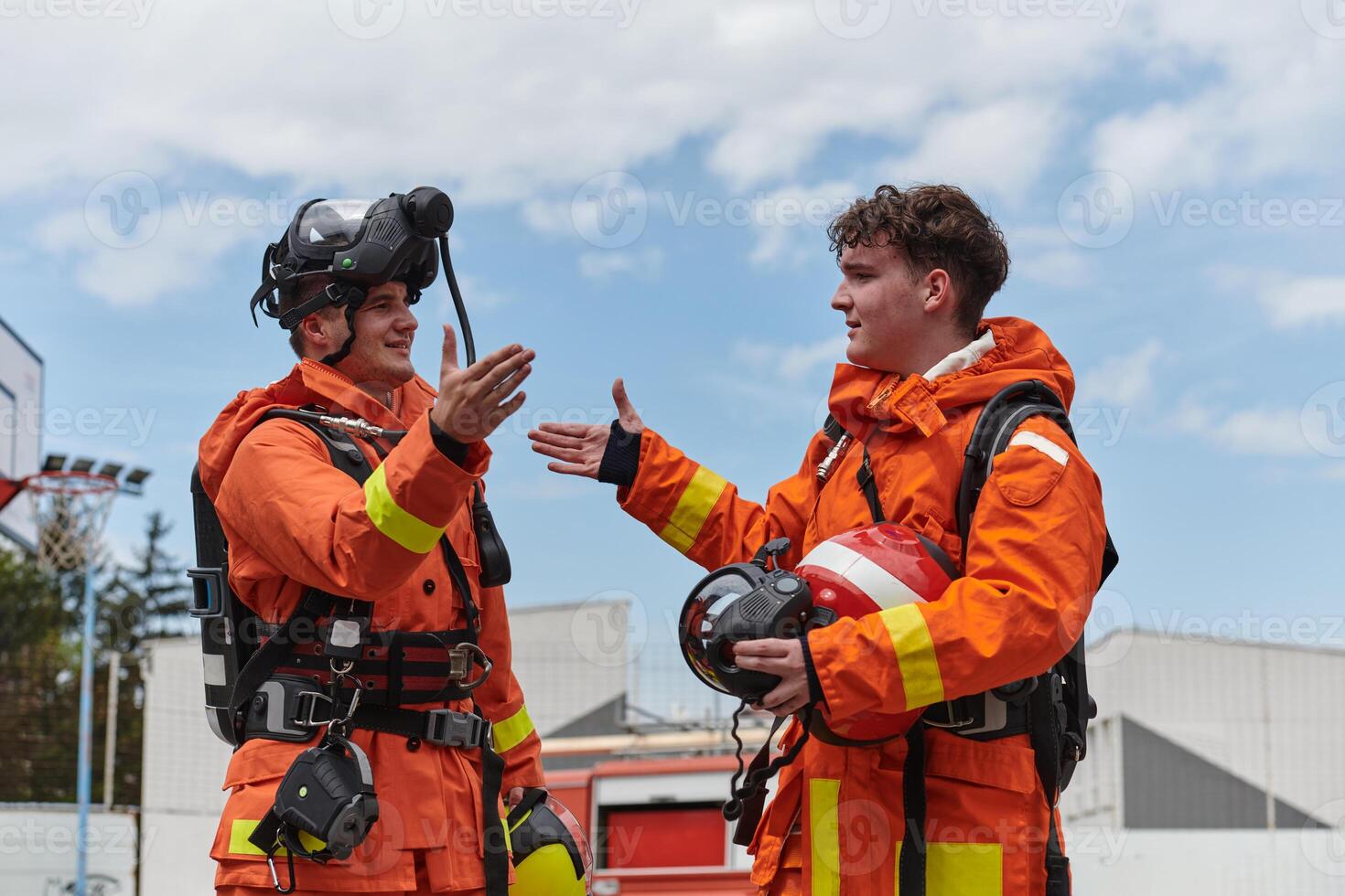 A unified team of firefighters, adorned in their uniforms, engages in a heartfelt celebration marked by triumphant salutes and cheers, embodying the joy and gratitude following the successful photo
