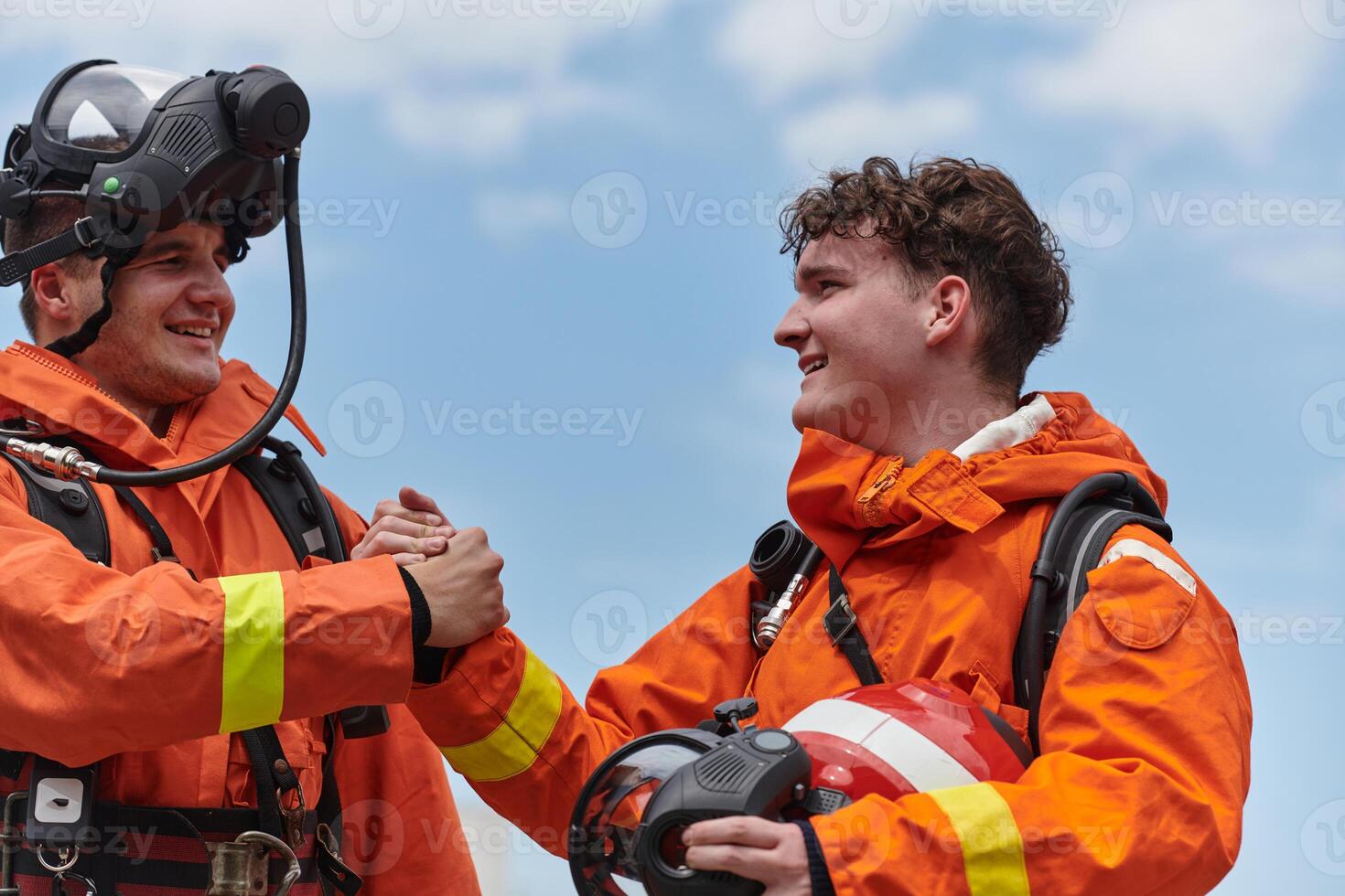A unified team of firefighters, adorned in their uniforms, engages in a heartfelt celebration marked by triumphant salutes and cheers, embodying the joy and gratitude following the successful photo