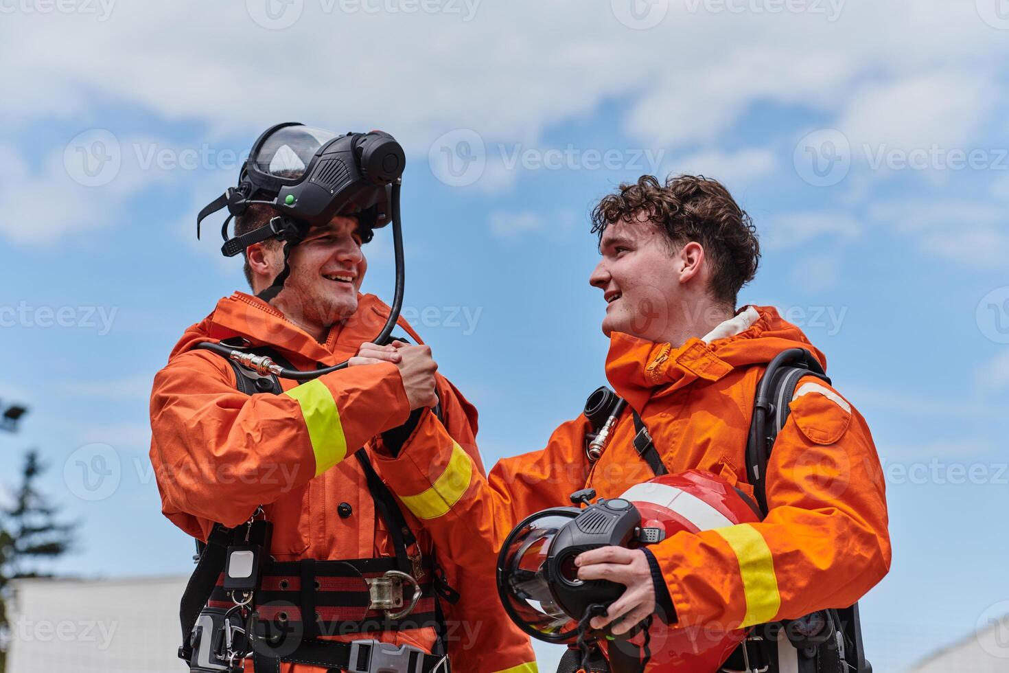 A unified team of firefighters, adorned in their uniforms, engages in a heartfelt celebration marked by triumphant salutes and cheers, embodying the joy and gratitude following the successful photo