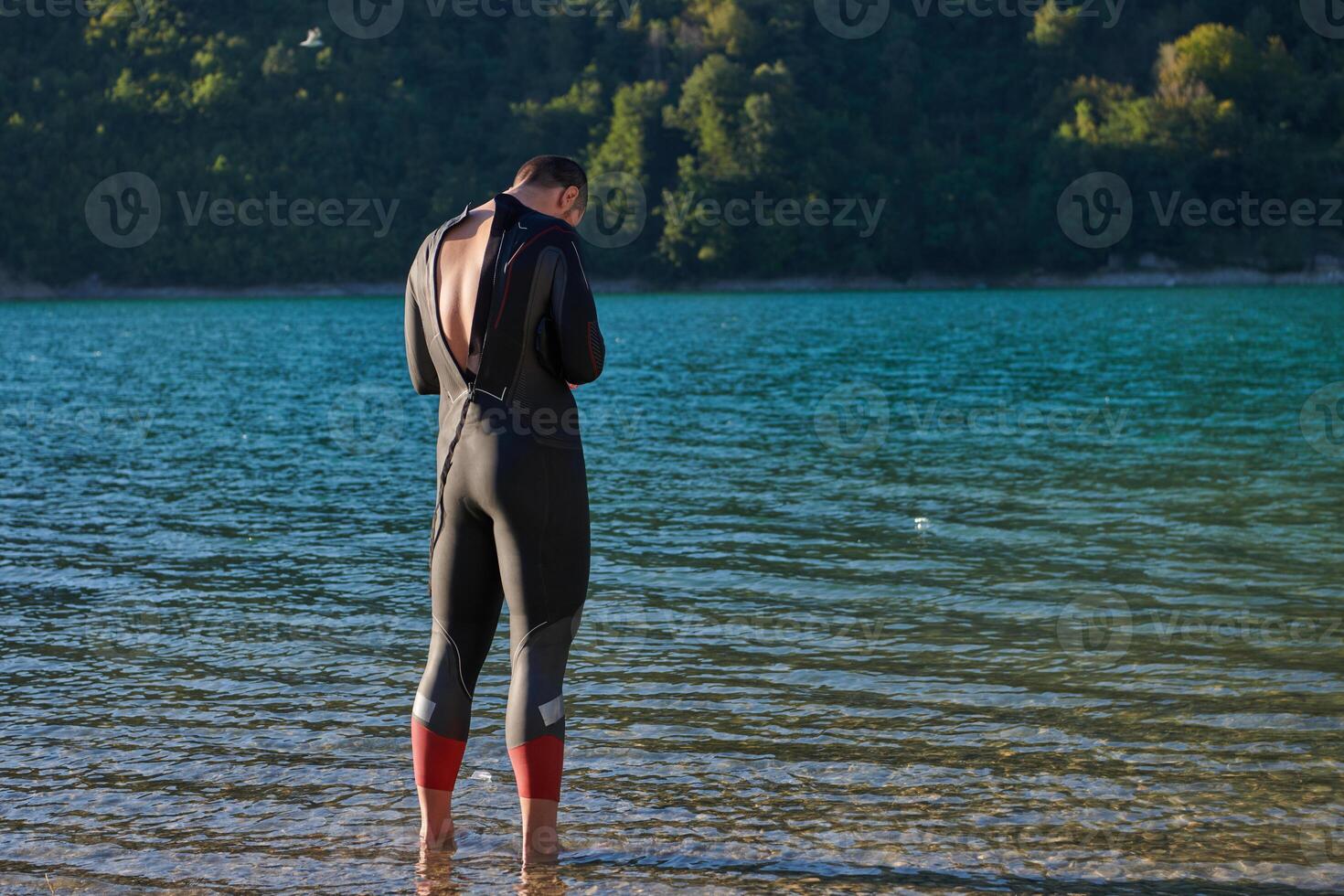 Authentic triathlon athlete getting ready for swimming training on lake photo