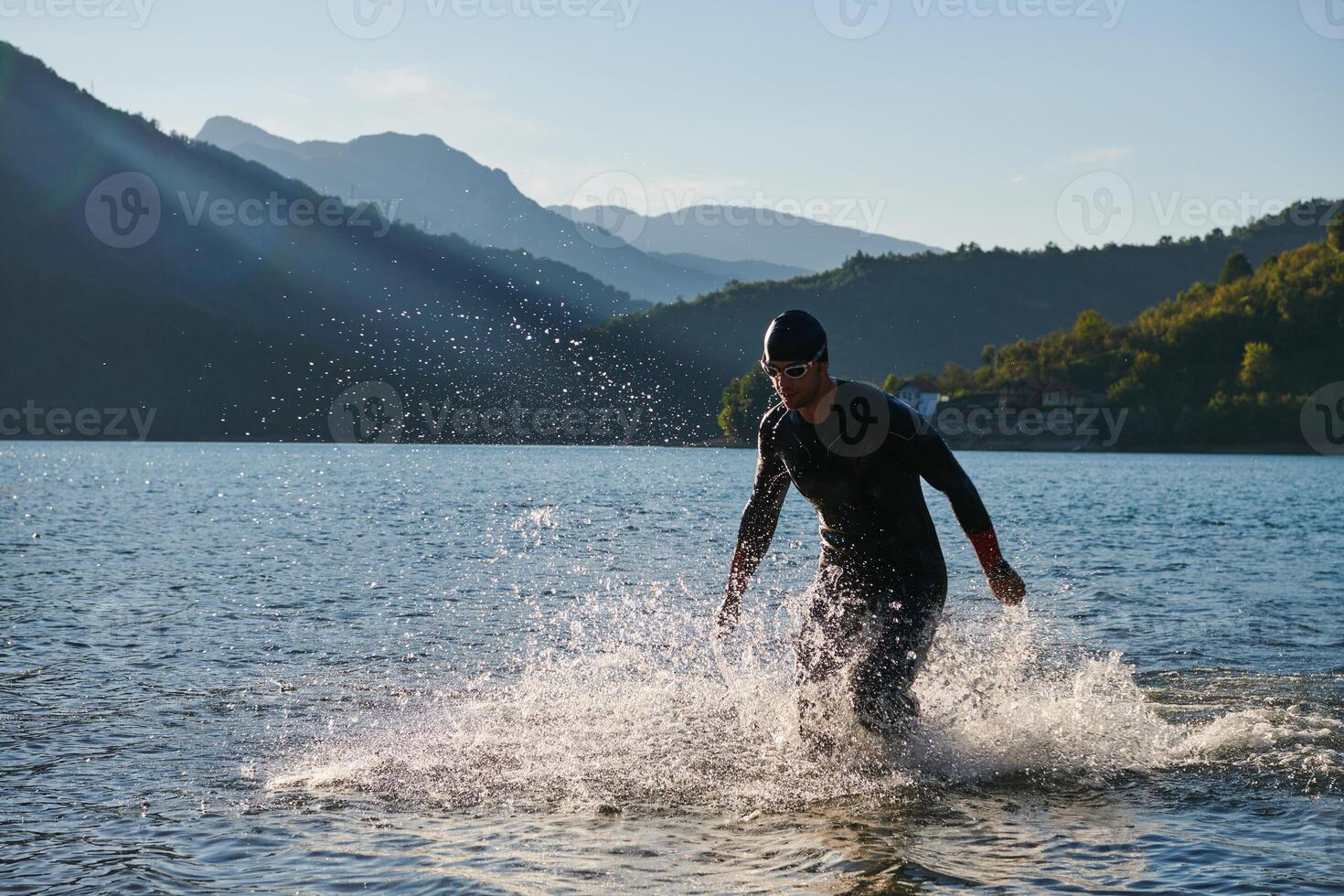 Triathlon athlete starting swimming training on lake photo