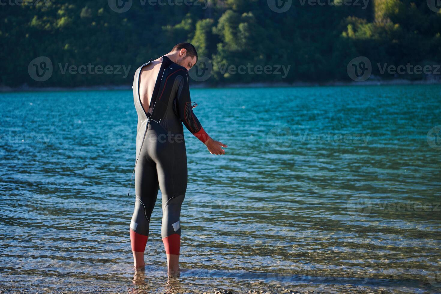 Authentic triathlon athlete getting ready for swimming training on lake photo