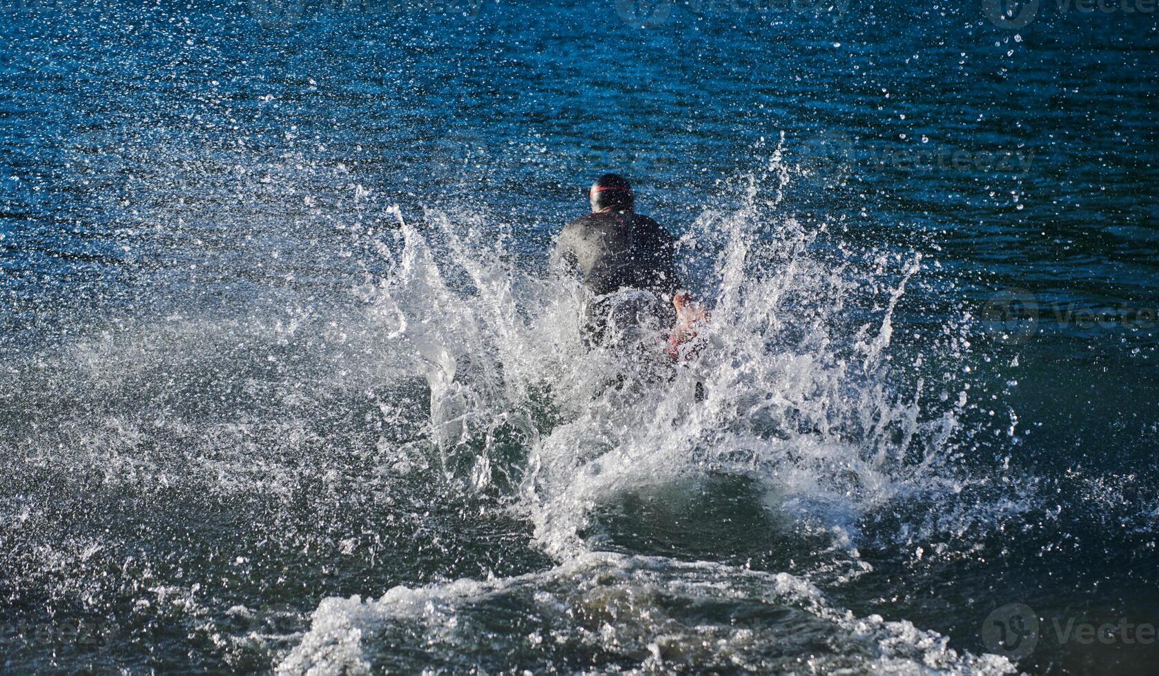 Triathlon athlete starting swimming training on lake photo