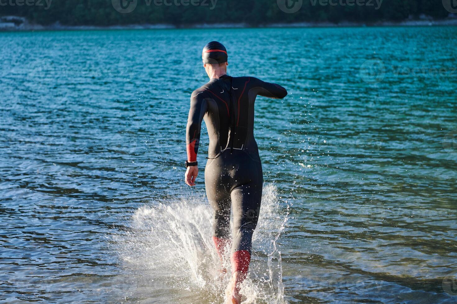 Triathlon athlete starting swimming training on lake photo