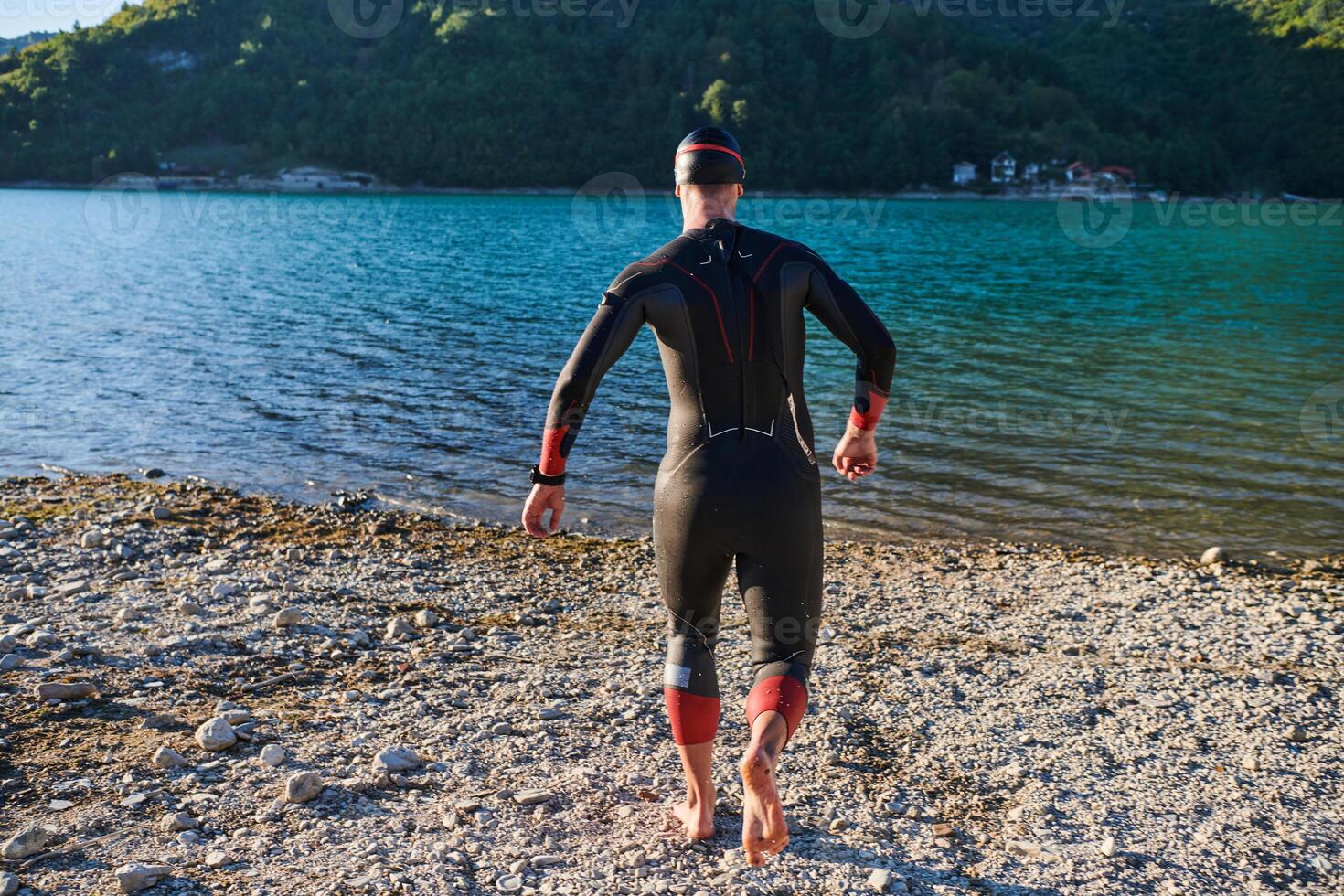 Authentic triathlon athlete getting ready for swimming training on lake photo