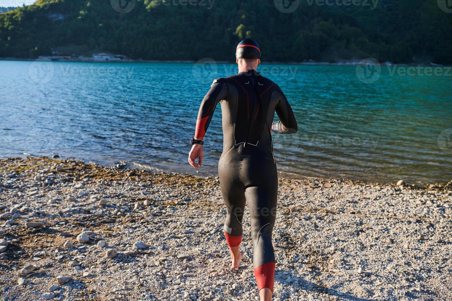 Authentic triathlon athlete getting ready for swimming training on lake photo
