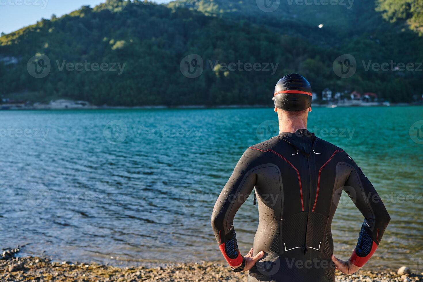 Authentic triathlon athlete getting ready for swimming training on lake photo