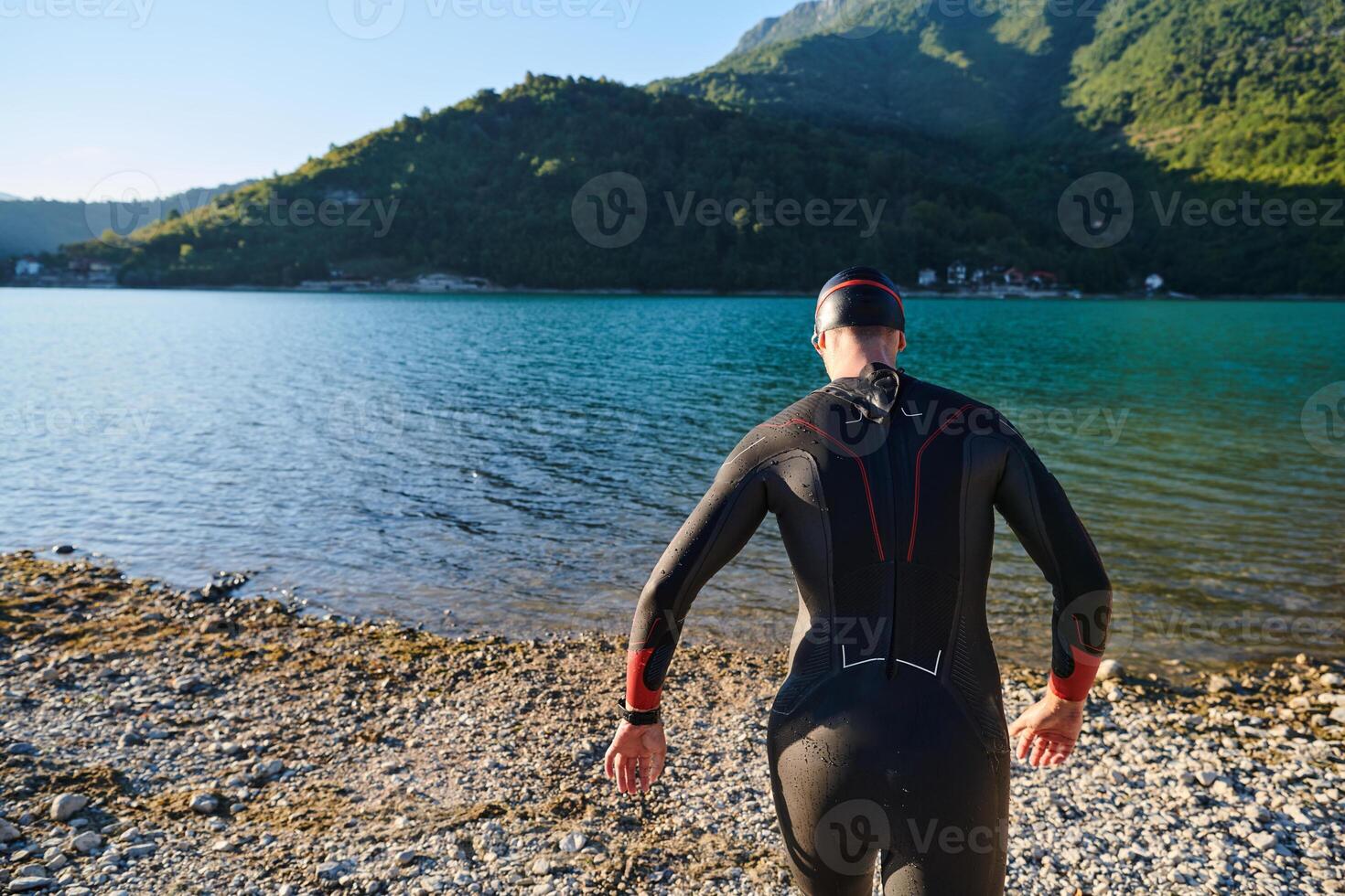 Authentic triathlon athlete getting ready for swimming training on lake photo