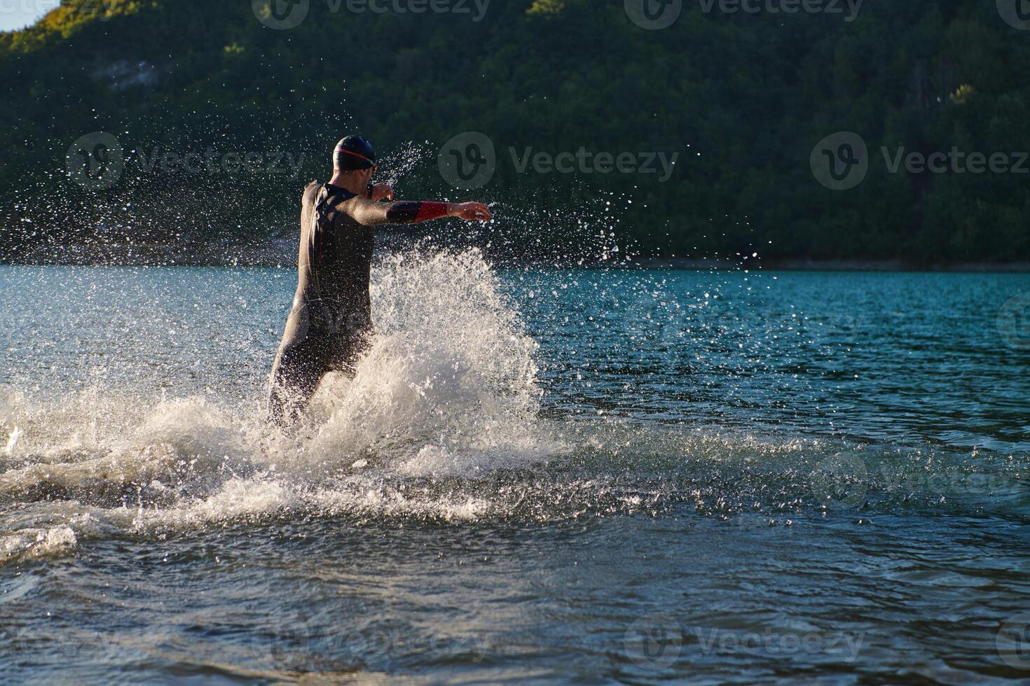 Triathlon athlete starting swimming training on lake photo