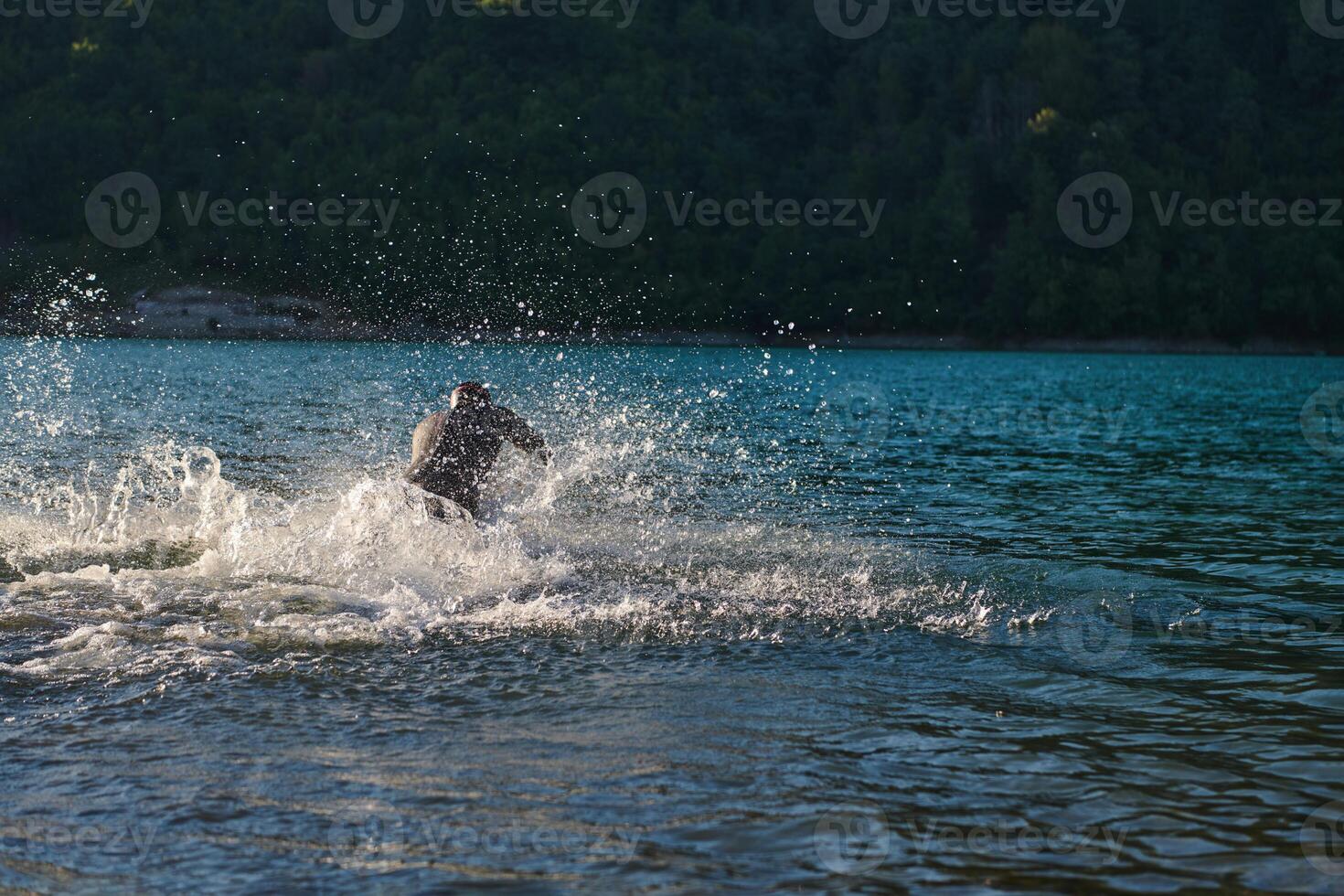 Triathlon athlete starting swimming training on lake photo