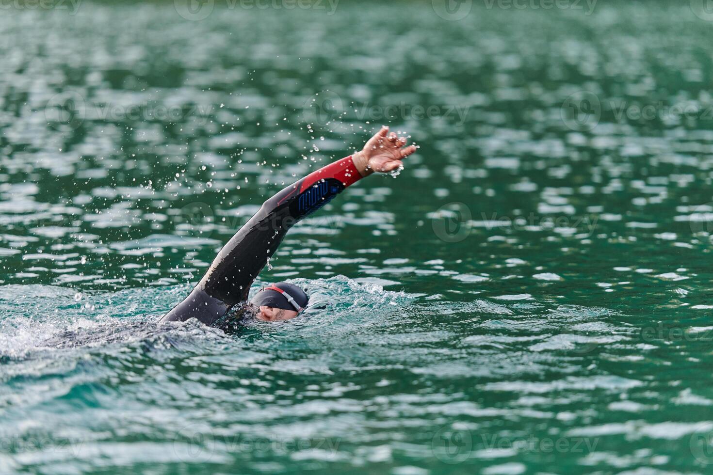 A professional triathlete trains with unwavering dedication for an upcoming competition at a lake, emanating a sense of athleticism and profound commitment to excellence. photo