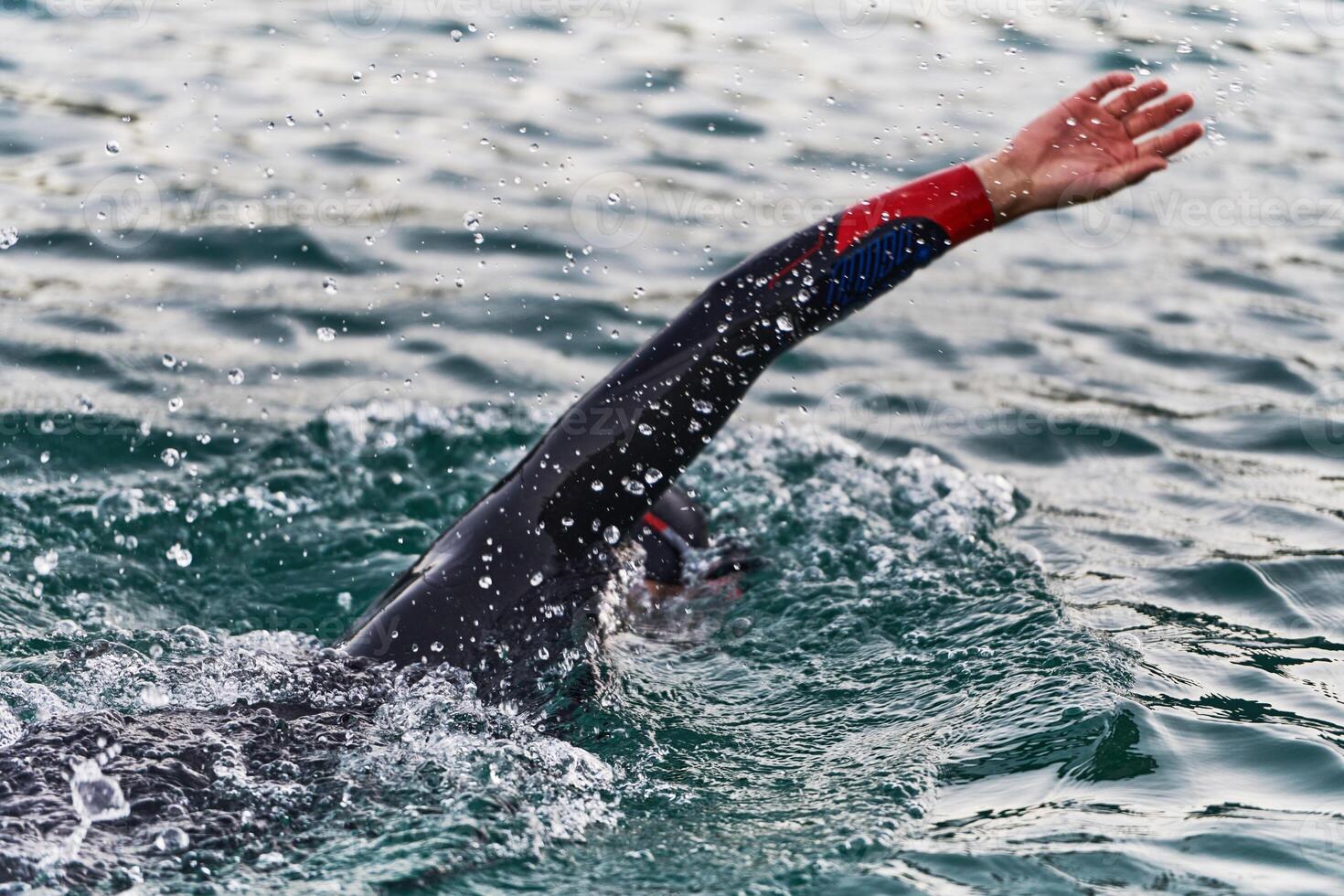 A professional triathlete trains with unwavering dedication for an upcoming competition at a lake, emanating a sense of athleticism and profound commitment to excellence. photo