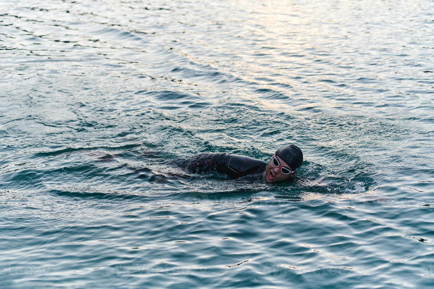A professional triathlete trains with unwavering dedication for an upcoming competition at a lake, emanating a sense of athleticism and profound commitment to excellence. photo