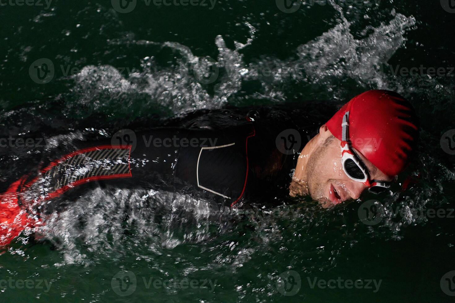 A determined professional triathlete undergoes rigorous night time training in cold waters, showcasing dedication and resilience in preparation for an upcoming triathlon swim competition photo