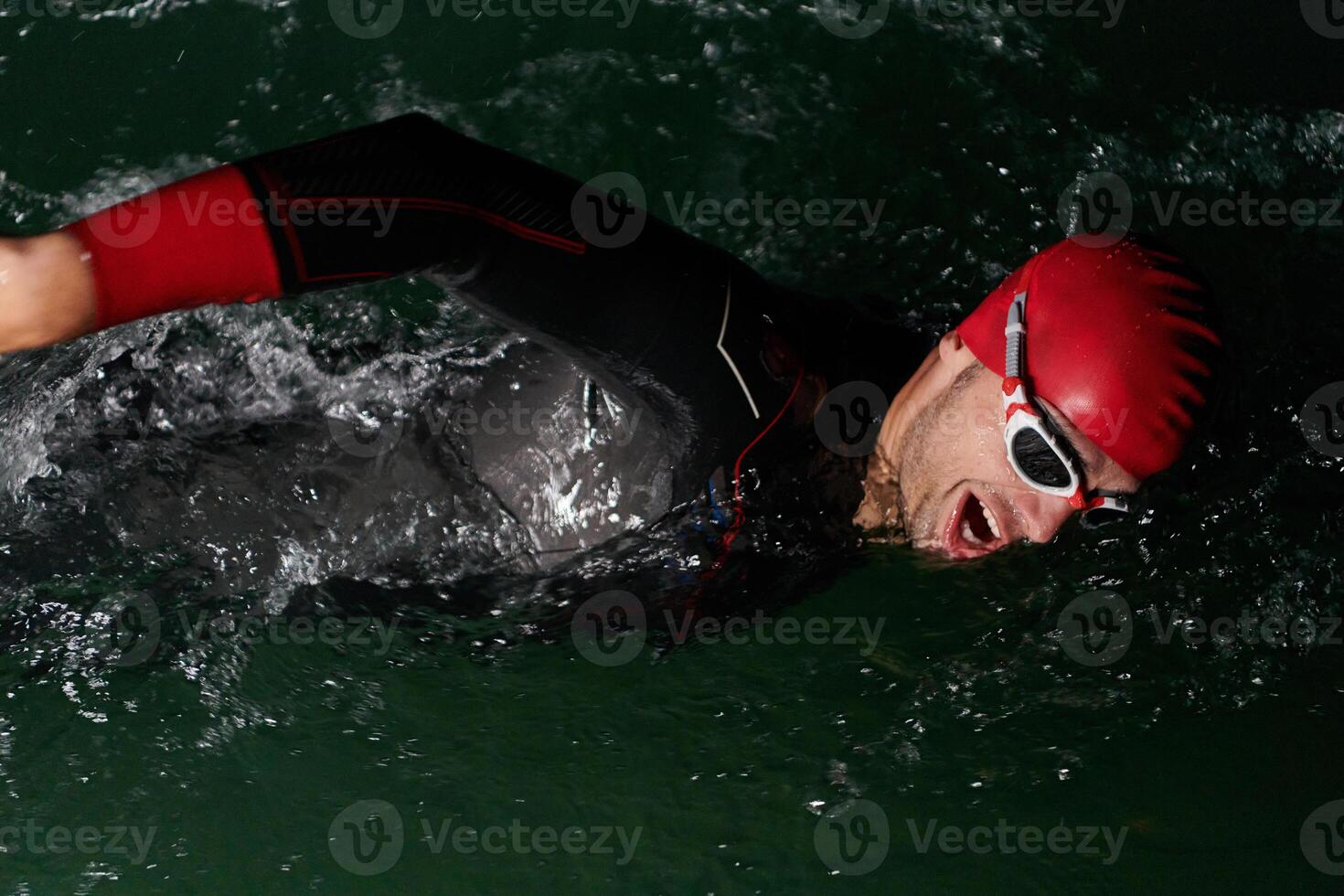 A determined professional triathlete undergoes rigorous night time training in cold waters, showcasing dedication and resilience in preparation for an upcoming triathlon swim competition photo