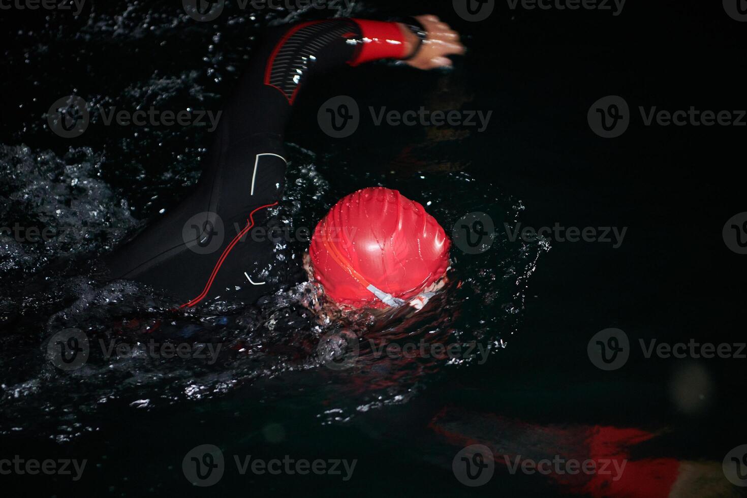 A determined professional triathlete undergoes rigorous night time training in cold waters, showcasing dedication and resilience in preparation for an upcoming triathlon swim competition photo