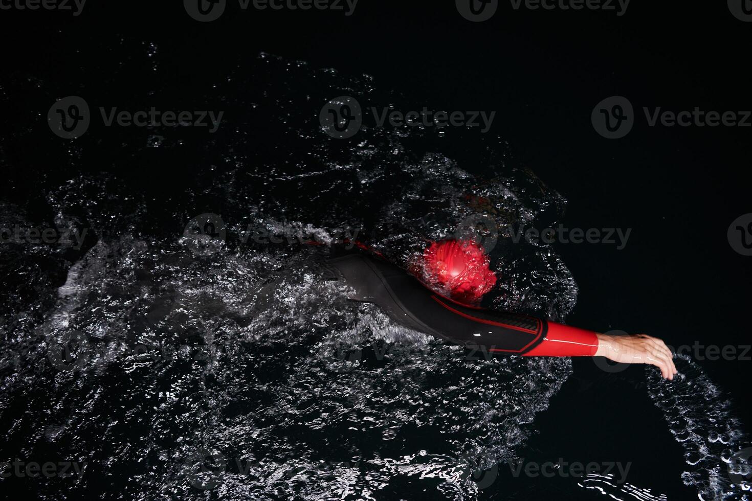A determined professional triathlete undergoes rigorous night time training in cold waters, showcasing dedication and resilience in preparation for an upcoming triathlon swim competition photo
